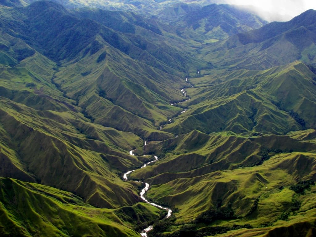 a picture of a river snaking in between mountains on either side